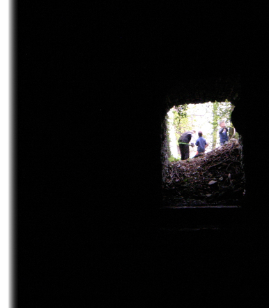 Una grotta buia da dove si vede una piccola apertura lumisosa con alcuni bambini che si apprestano ad entrare.